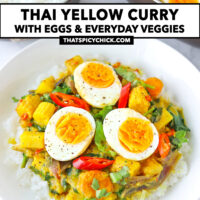 Front view of egg curry on rice on plate. Wok with curry and bowl with rice behind. Text overlay "Thai Yellow Curry with Eggs & Everyday Veggies" and "thatspicychick.com".