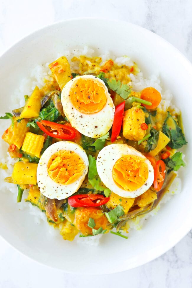 Top view of yellow egg curry on rice on a plate