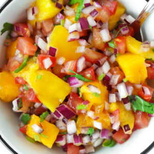 Close-up top view of bowl with mango salsa and a spoon.