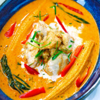 Close-up of chicken curry in small blue bowl. Text overlay "Thai Panang Chicken Curry", "Quick & Easy and "thatspicychick.com".