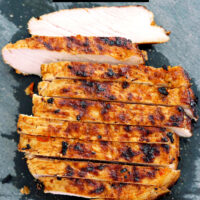 Sliced grilled pork steak on a cutting board. Text overlay "Vietnamese Grilled Pork Steaks" and "thatspicychick.com".