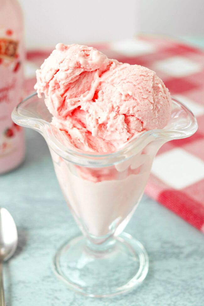 Scoops of strawberry ice cream in a tall ice cream glass.