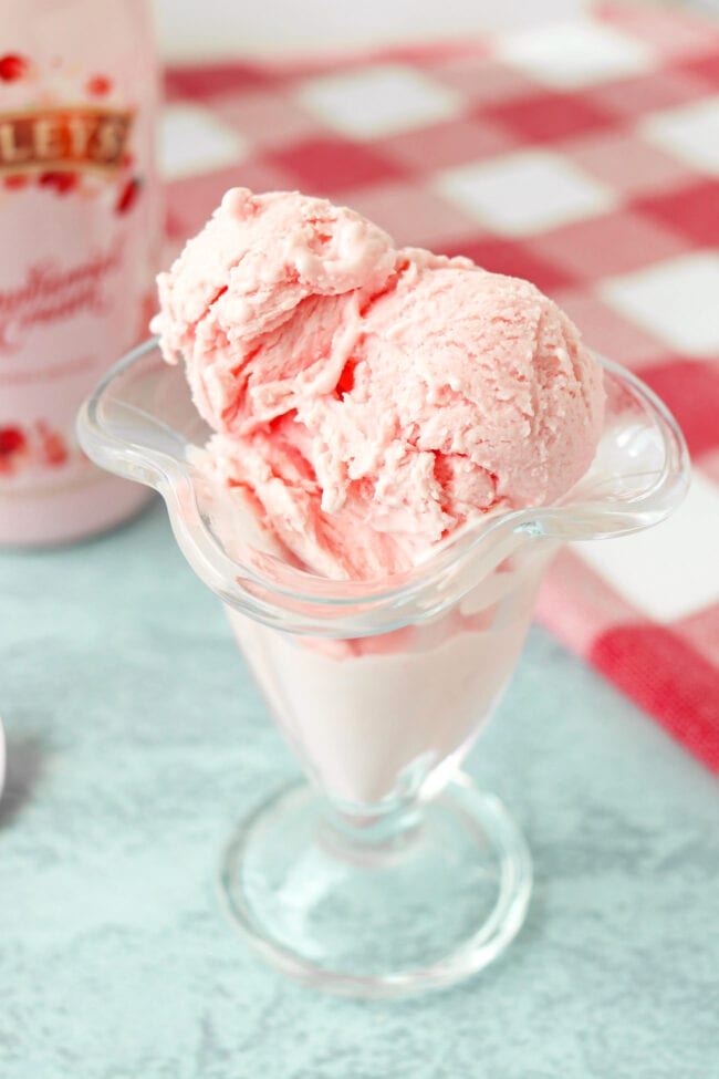 Front view of scoops of strawberry ice cream in a tall ice cream glass.