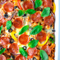 Top view of pasta bake with pizza toppings in a baking dish. Text overlay "Pizza Pasta Bake", "A delicious pasta dinner the whole family will love!" and "thatspicychick.com"