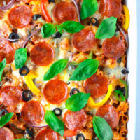 Top view of pizza pasta casserole garnished with basil leaves in a baking dish.