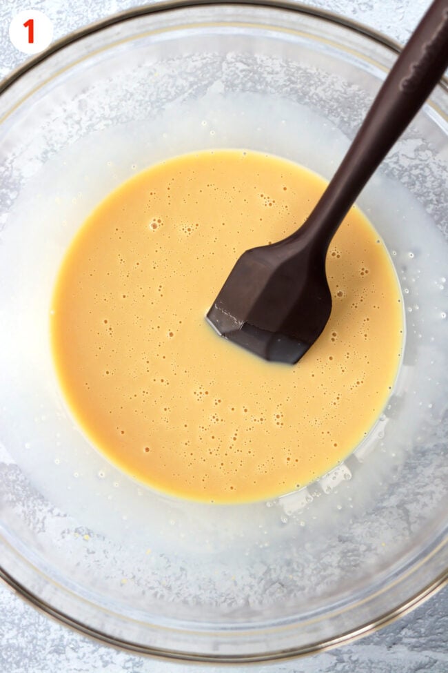 Sweetened condensed milk and flavorings mixture in a mixing bowl with a silicone spatula.