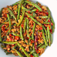 Close-up top view of green beans and ground pork stir-fry in a serving bowl.