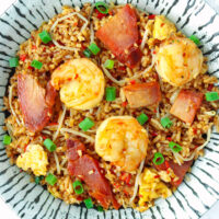 Top view of fried rice with char siu pork and shrimp on a plate.