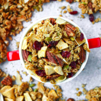 Top view of granola in a bowl. Text overlay "Apple Pie Granola", "Healthy | Vegan | Gluten-free", and "thatspicychick.com".