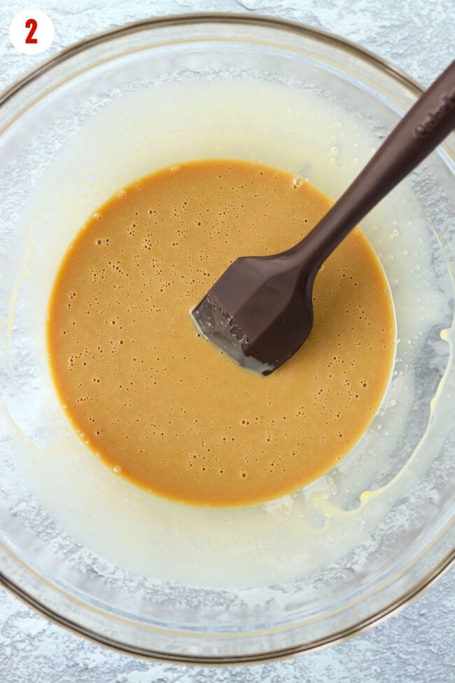Sweetened condensed milk and flavorings mixture in a large mixing bowl with a silicone spatula.