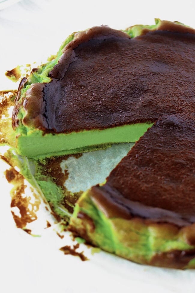 Pandan burnt cheesecake with a slice cut out to show the inside.