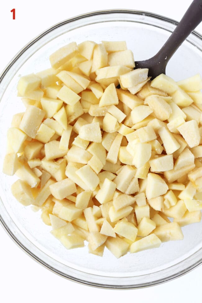 Diced apples tossed with flour in a large mixing bowl.