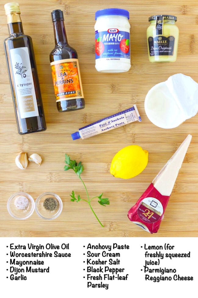 Labeled ingredients for Caesar salad dressing on a wooden board.
