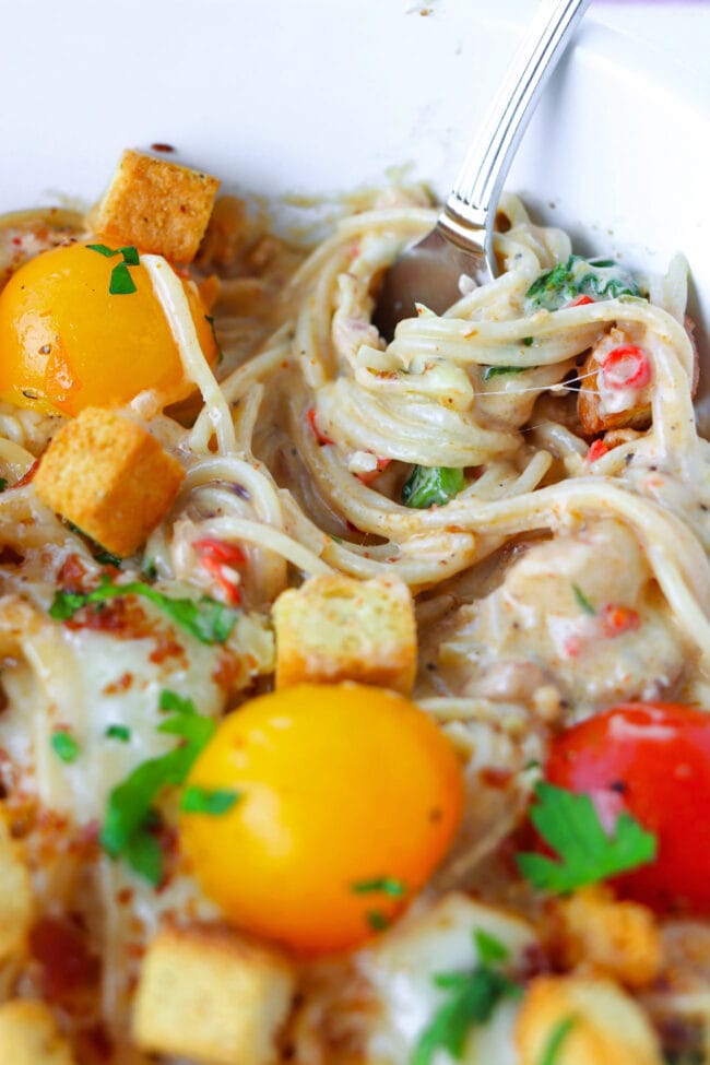 Capellini twirled around fork in pasta bake dish.