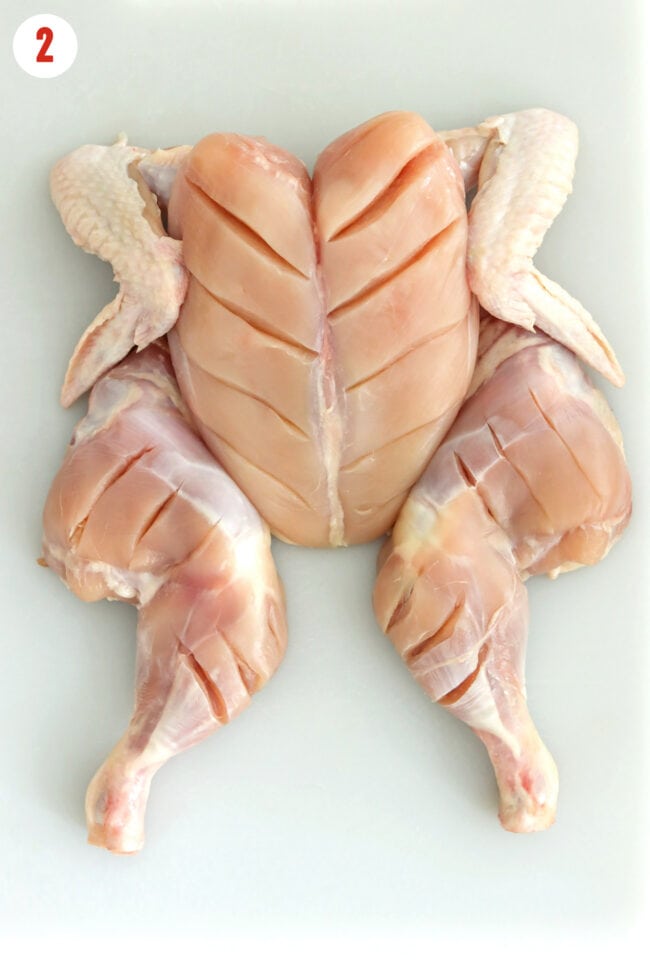Spatchcocked skinless chicken with deep slits in breasts, thighs, and legs.