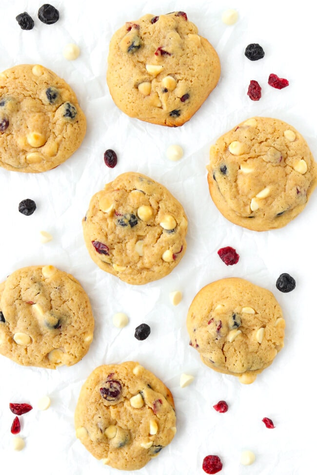 Soft muffin cookies surrounded with dried berries and white chocolate chips on parchment paper.