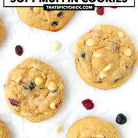Cookies on parchment paper surrounded by dried berries and white chocolate chips. Text overlay "Dried Berries & White Chocolate Soft Muffin Cookies" and "thatspicychick.com".