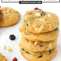 Close-up of stacked cookies on parchment paper. Text overlay "Dried Berries & White Chocolate Soft Muffin Cookies" and "thatspicychick.com".