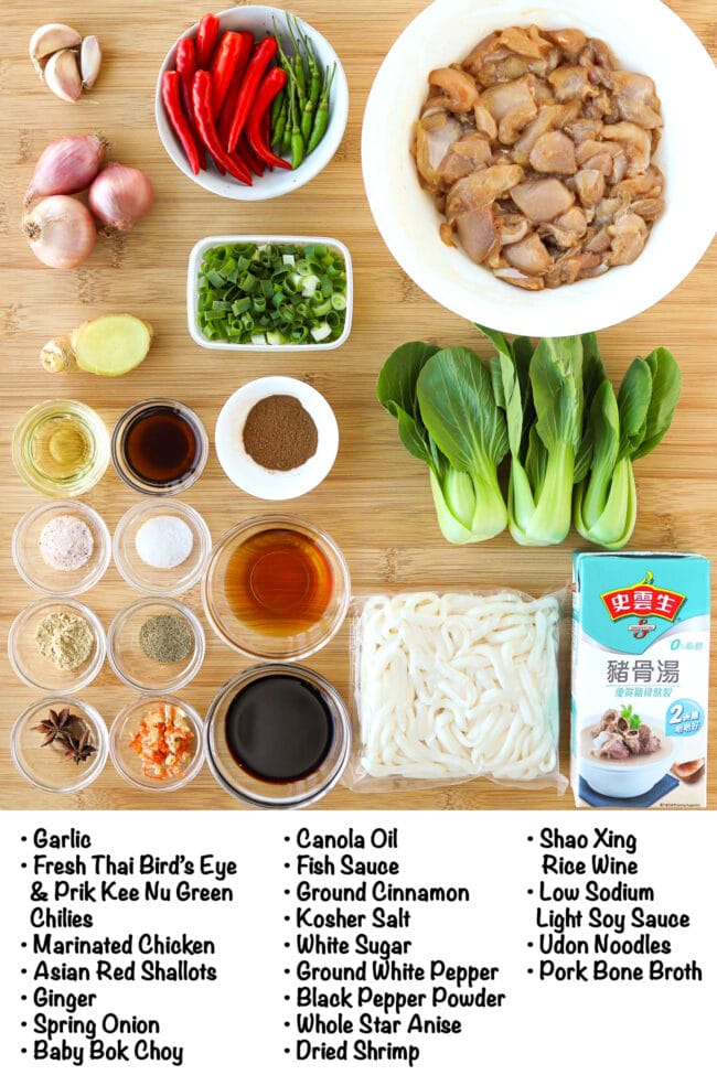 Labeled ingredients for Spicy Udon Noodle Soup with Chicken & Mushrooms on a wooden board.