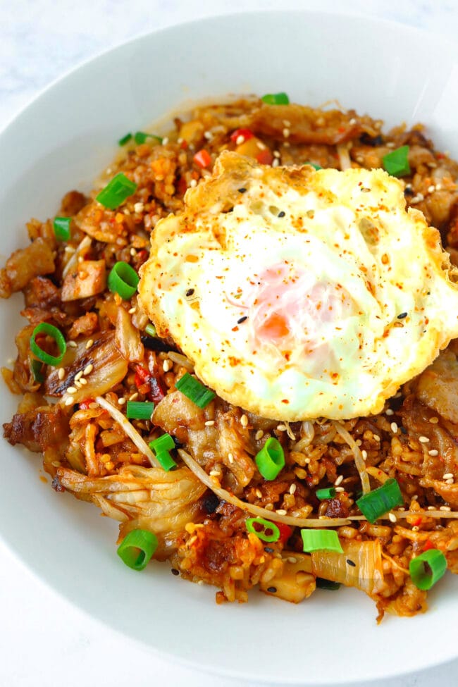 Closeup front view of plate with kimchi fried rice topped with a fried egg.