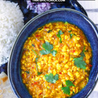Bowl with paneer bhurji on a plate with rice. Text overlay "Paneer Bhurji Gravy", "Scrambled Cottage Cheese with Onion & Tomato Gravy", and "thatspicychick.com".