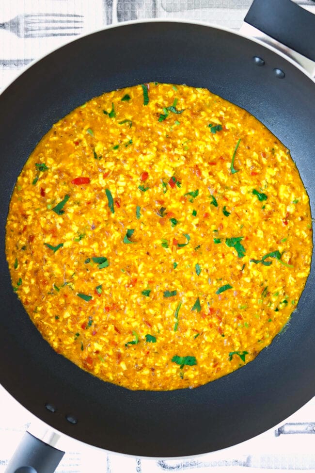 Scrambled Indian cottage cheese dish in a black wok.
