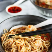Bowl of noodles with chopsticks. Text overlay "Dan Dan Noodles with Spicy Soup & Wontons" and "thatspicychick.com".