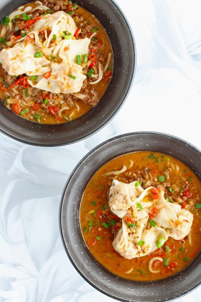 Two bowls with spicy Sichuan pork soup noodles topped with wontons.