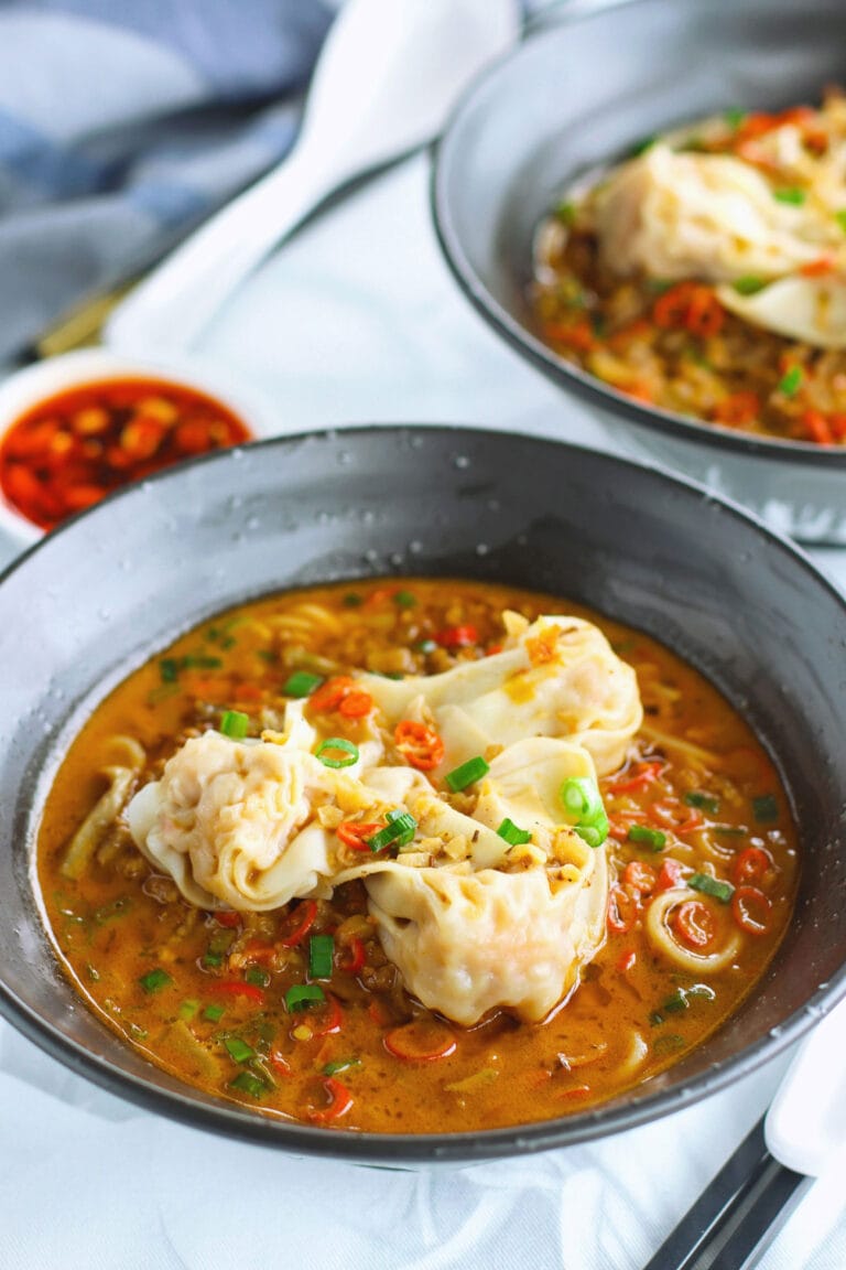 Closeup front view of spicy noodles soup with pork and wontons.