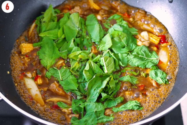 Added holy basil leaves to wok with pork and simmering broth.