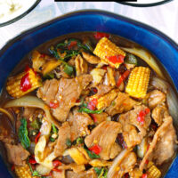 Pork stir-fry in serving bowl and two bowls with rice. Text overlay "Thai Basil Pork with Juicy Pork Collar" and "thatspicychick.com".