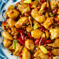 Closeup top view of plate with chicken stir-fry with dried chilies. Text overlay "The Best Kung Pao Chicken" and "thatspicychick.com.