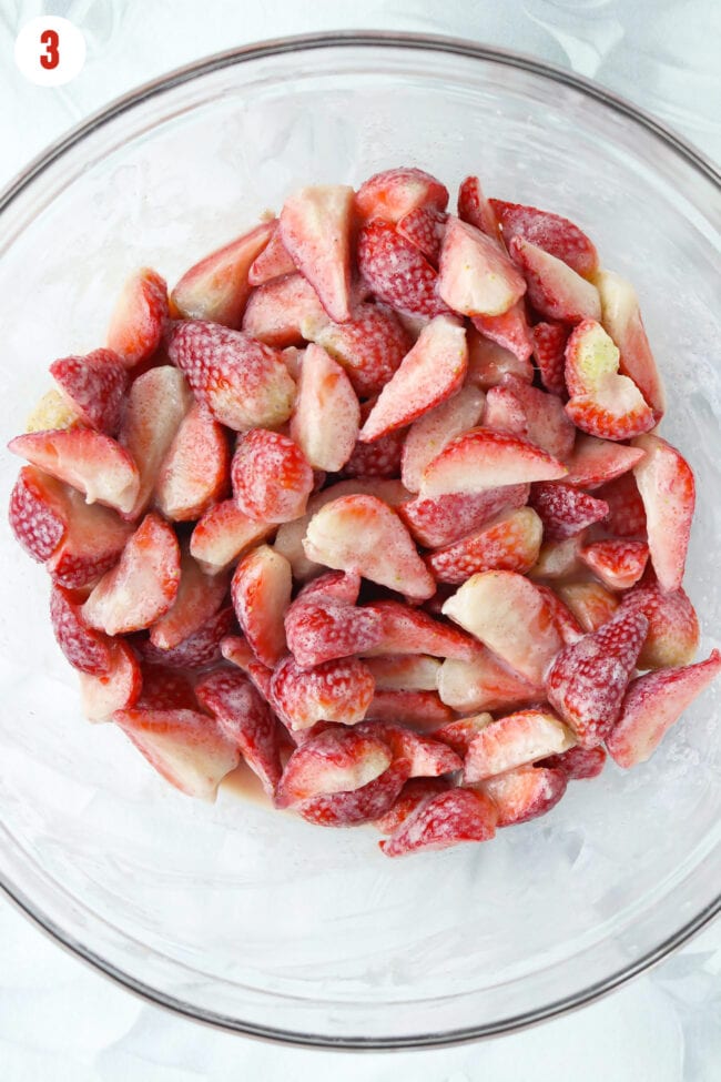 Sliced strawberries tossed with cornstarch, sugar, vanilla extract, and Baileys Strawberries & Cream in mixing bowl.