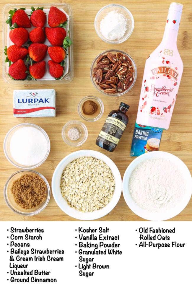 Labeled ingredients for Strawberry Crisp with Baileys Strawberries & Cream on a wooden board.