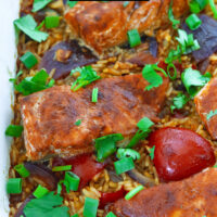 Front view closeup of fish and rice in baking dish. Text overlay "Thai Chili Jam Salmon & Rice Bake" and "thatspicychick.com".