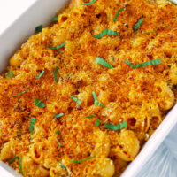 Diagonally placed dish with mac and cheese. Text overlay "XO Sauce Mac and Cheese with Buttery Shrimp" and "thatspicychick.com".
