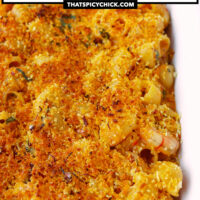 Closeup front view of baking dish with mac and cheese. Text overlay "XO Sauce Mac and Cheese with Juicy Shrimp & Spicy Breadcrumbs Topping" and "thatspicychick.com".