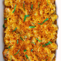 Baking dish with mac and cheese with crunchy breadcrumbs topping. Text overlay "XO Sauce Mac and Cheese with Shrimp" and "thatspicychick.com".
