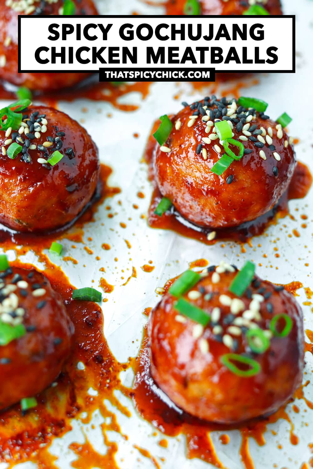 Baked Korean meatballs garnished with spring onion and sesame seeds on a sheet of foil. Text overlay "Spicy Gochujang Chicken Meatballs" and "thatspicychick.com".