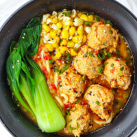 Top view of bowl with spicy miso ramen with chicken meatballs, corn, and bok choy.