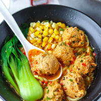 Chicken meatball in spicy broth with noodles in a bowl. Text overlay "Spicy Miso Ramen with Juicy Chicken Meatballs" and "thatspicychick.com".