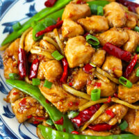 Closeup front view of a spicy chicken stir-fry dish on a plate. Text overlay "Chicken in Vinegar Sauce", "Sichuan Cu Liu Ji", and "thatspicychick.com".