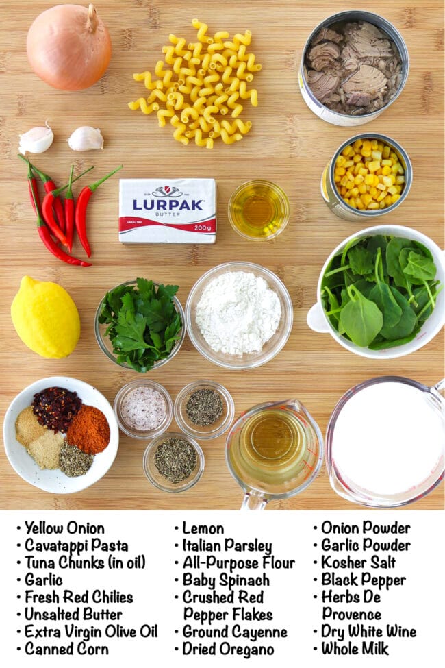 Labeled ingredients to make Creamy Tuna Pasta Bake on a wooden board.