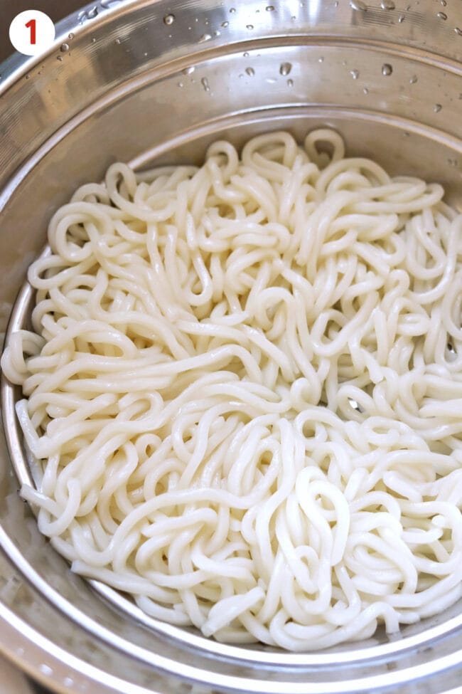Cooked and drained white Shanghai noodles in a colander.