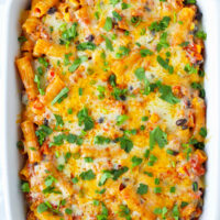 Baked pasta dish with cheesy topping. Text overlay "Spicy Chicken Enchilada Pasta", "Cheesy | Spicy | 30-Minute Meal" and "thatspicychick.com".