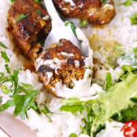 Cut kofta on a spoon with garlic sauce on rice in a plate. Text overlay "Spicy Kofta with Lamb and Chicken" and "thatspicychick.com".