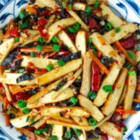 Closeup of plate with spicy tofu stir-fry. Text overlay "Tofu with Hot Garlic Sauce", "Sichuan Yu Xiang Style" and "thatspicychick.com".