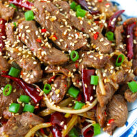 Closeup front view of plate with lamb stir-fry. Text overlay "Mongolian Lamb Stir-fry" and "thatspicychick.com".