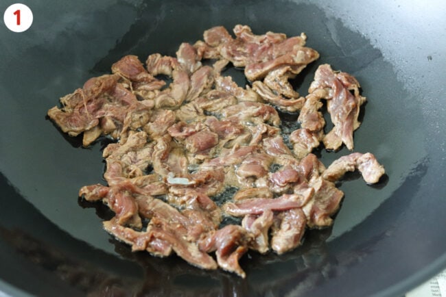 Cooking marinated lamb strips in a wok.