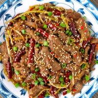 Plate with lamb stir-fry with chilies. Text overlay "Mongolian Lamb Stir-fry" and "thatspicychick.com".